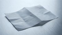 Crumpled white tissue paper sheets on clean surface creating soft shadows and delicate texture for hygiene and healthcare concepts.