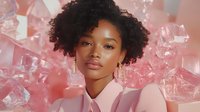 Young African American woman with natural curly hair against pink background with ice cubes, wearing pink blazer, expressing confidence and modern beauty.