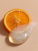 Fresh orange slice with sparkling sugar crystals on beige background, minimalist food composition highlighting natural texture and sweetness.