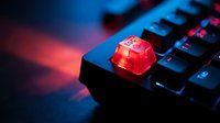 Red translucent escape key on mechanical gaming keyboard with dramatic blue and red lighting effects for technology and gaming concepts.