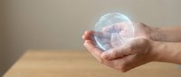 Hands holding glowing transparent sphere with pink embryo inside representing fertility, pregnancy, life creation and reproductive health concept.