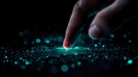 Finger touching glowing digital surface with turquoise light particles and bokeh effects on dark background, representing futuristic technology interface.