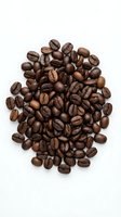 Fresh roasted coffee beans scattered on white background, isolated for cafe menu design, beverage branding and culinary projects.