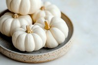 Mini white pumpkins arranged on rustic ceramic plate against light background, seasonal autumn decor for farmhouse style interior design and holiday decoration.