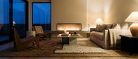 Modern luxury living room with contemporary furniture, warm lighting, and floor-to-ceiling windows overlooking evening cityscape. Suitable for interior design, real estate, and home decor projects.