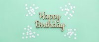 Wooden Happy Birthday lettering on mint green background with white confetti, flat lay banner for greeting card or celebration design.