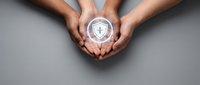 Two hands holding a glowing shield icon with a checkmark symbol, representing data protection, cybersecurity, and digital safety for business and technology concepts.