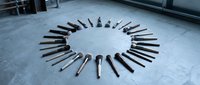 Professional makeup brushes arranged in a circle on a concrete floor, showcasing a complete collection of cosmetic tools for beauty and artistry.