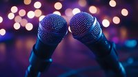 Professional microphones on stage with blurred bokeh lights in background, creating atmospheric entertainment and music performance ambiance.