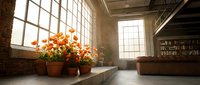 Cozy loft apartment interior with orange flowers on windowsill, exposed brick walls, large windows and warm natural lighting for home decor concepts.