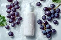 White cosmetic bottle with water drops surrounded by fresh dark purple grape clusters and green leaves on light background for natural skincare product.