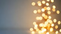 Warm golden bokeh lights creating soft blurred circles on neutral background for holiday decorations, celebrations, and festive atmosphere designs.