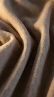 Close-up of soft, draped fabric with warm golden lighting creating deep shadows and texture. Suitable for backgrounds, textile design, and fashion projects.