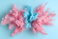Pink and blue powder explosion creating symmetrical abstract cloud formation against light blue background, capturing dynamic motion and color contrast.