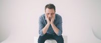 Stressed middle-aged Caucasian man sitting on bed holding head in hands showing depression, anxiety, mental health struggles, burnout syndrome.