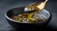 Golden spoon dripping aromatic Asian dipping sauce with sesame seeds into dark ceramic bowl, close-up view on dark background for food photography and menu design.