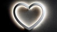 Glowing heart-shaped neon light with warm white illumination against dark textured background for romantic decor and Valentine's Day designs.