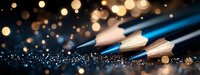 Blue wooden pencils on dark surface with golden bokeh lights and glitter sparkles creating magical artistic atmosphere for creative inspiration.