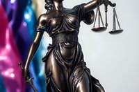 Bronze statue of Lady Justice holding scales and sword against colorful blurred background, symbolizing law, justice and legal system principles.