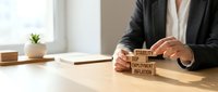 Businessperson stacking wooden blocks with economic terms stability, GDP, employment, inflation on desk, symbolizing financial planning and macroeconomic analysis.