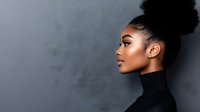 Young African American woman with natural curly hair in bun, wearing black turtleneck, photographed in profile against gray background showing elegant beauty and confidence.