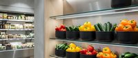 Modern grocery store produce section with colorful fresh vegetables displayed on shelves including bell peppers, cucumbers and other organic produce for healthy eating.