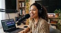 Young Hispanic woman podcaster recording audio content in professional home studio setup with microphone, headphones and laptop for broadcasting.
