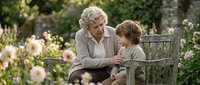 Elderly Caucasian grandmother with curly gray hair sharing tender moment with young grandson on wooden garden bench surrounded by blooming roses in peaceful outdoor setting.