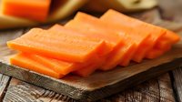 Fresh sliced papaya arranged in a row on rustic wooden cutting board, showing bright orange flesh and natural texture, ready for healthy eating.