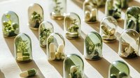 Small green plants and pills in glass domes arranged on white surface, concept of natural medicine and alternative herbal treatment approach for healthcare.
