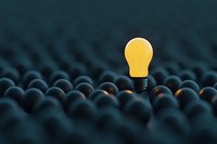 Glowing yellow lightbulb standing out among dark ones, representing innovation, leadership and creative thinking in business concept background.