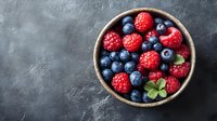 Fresh organic blueberries and raspberries in rustic ceramic bowl on dark concrete background, top view. Natural antioxidant berries for healthy eating.