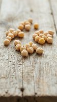 Roasted chickpeas scattered on weathered wooden surface, showcasing legume nutrition and healthy snacking options for food and wellness content.