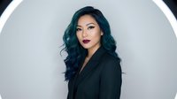 Professional Asian businesswoman with teal hair in black blazer against modern circular background for corporate branding and marketing materials.