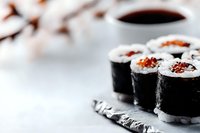 Fresh sushi rolls with rice and filling on gray stone plate against light background. Close up view with selective focus and copy space for menu design.