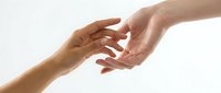Two hands reaching toward each other in gentle connection against clean white background symbolizing help, support, trust and human compassion.