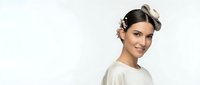 Young woman with elegant vintage hairstyle and decorative hair accessories smiling warmly at camera against clean white background for design projects.