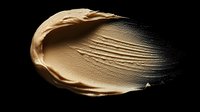 Smooth beige foundation cream smear with gradient texture on black background, showing cosmetic product consistency for makeup artists and beauty industry.