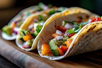 Fresh Mexican street tacos filled with colorful vegetables, diced tomatoes, onions, and cilantro served on rustic wooden board, close up view of authentic cuisine.