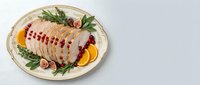 Sliced duck breast arranged on decorative plate with fresh rosemary, figs, and orange segments for fine dining presentation and gourmet food styling.