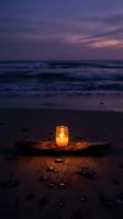 Glowing candle in glass jar on driftwood at twilight beach with purple sunset sky and ocean waves creating peaceful romantic atmosphere for meditation and relaxation.