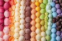 Colorful ice cream scoops arranged in rainbow pattern rows showing various flavors from pink to purple, creating vibrant dessert background for food industry.