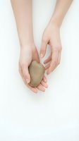 Gentle hands cupping smooth river stone on white background for wellness, meditation and spa therapy concepts.