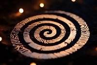 Mesmerizing spiral pattern with intricate tribal design illuminated by warm bokeh lights creates mystical atmosphere for spiritual and meditation backgrounds.