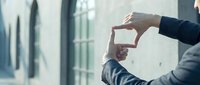 Business professional making frame gesture with hands in modern office environment for creative vision and planning concepts.