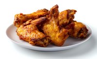 Crispy golden chicken wings with spicy sauce served on white plate, close up view of juicy fried poultry appetizer for restaurant menu or cooking blog.
