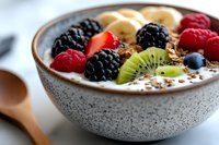 Healthy breakfast bowl with fresh berries, kiwi, banana and granola in ceramic bowl. Nutritious morning meal for wellness and diet lifestyle.