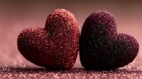 Two sparkling glittery hearts in red and burgundy colors on shimmering surface for Valentine's Day romance celebration and love themed designs.