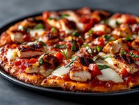 Fresh homemade pizza with melted mozzarella, grilled chicken, red peppers and herbs served on dark plate, close up view of crispy crust and savory toppings.