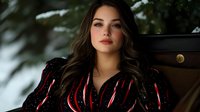 Young Hispanic woman in black and red velvet dress with long dark wavy hair poses outdoors in winter setting against snowy background, dramatic fashion portrait.